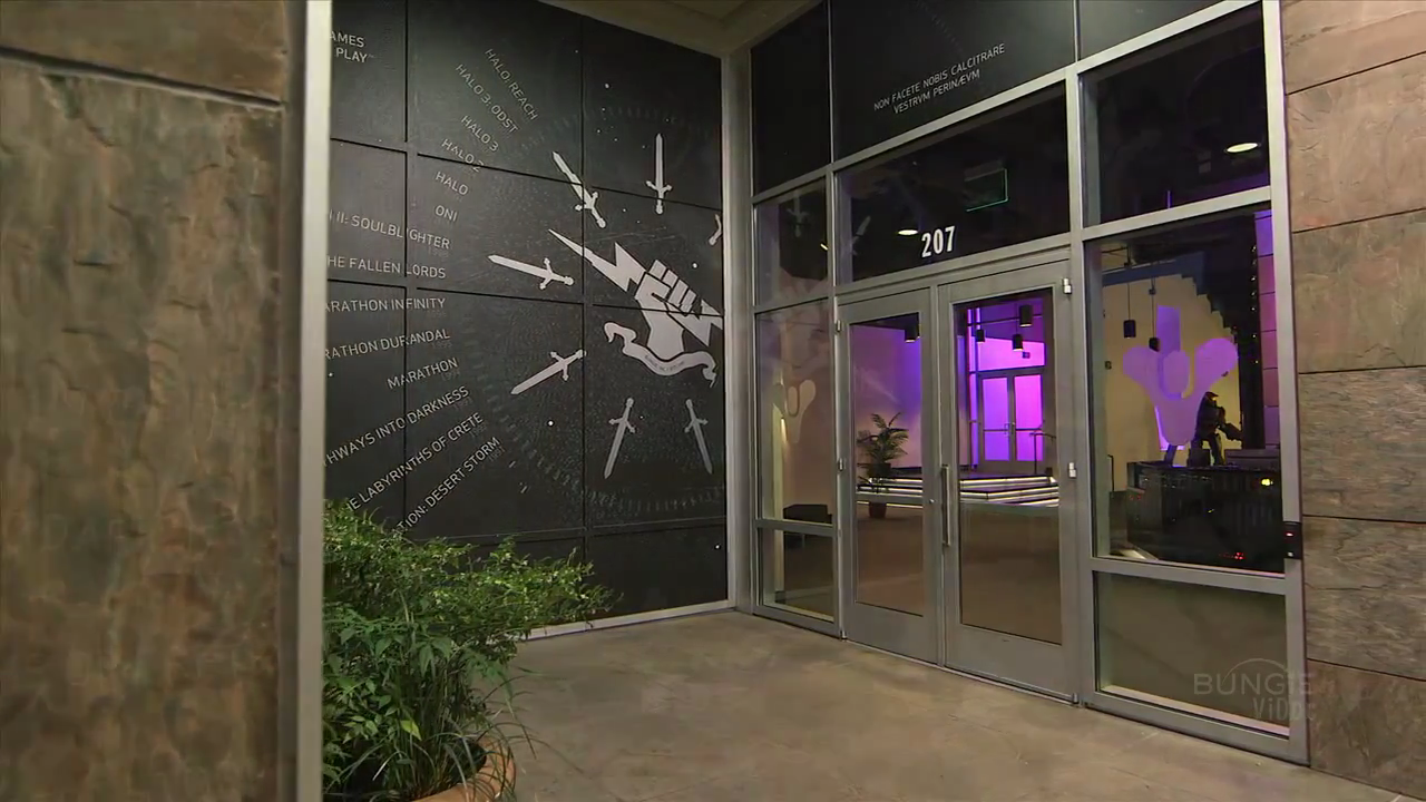 Bungie's outer lobby shows their company history, as well as more recent Destiny tricorn logo.  "Don't make us kick your ass" is written above the door in Latin.